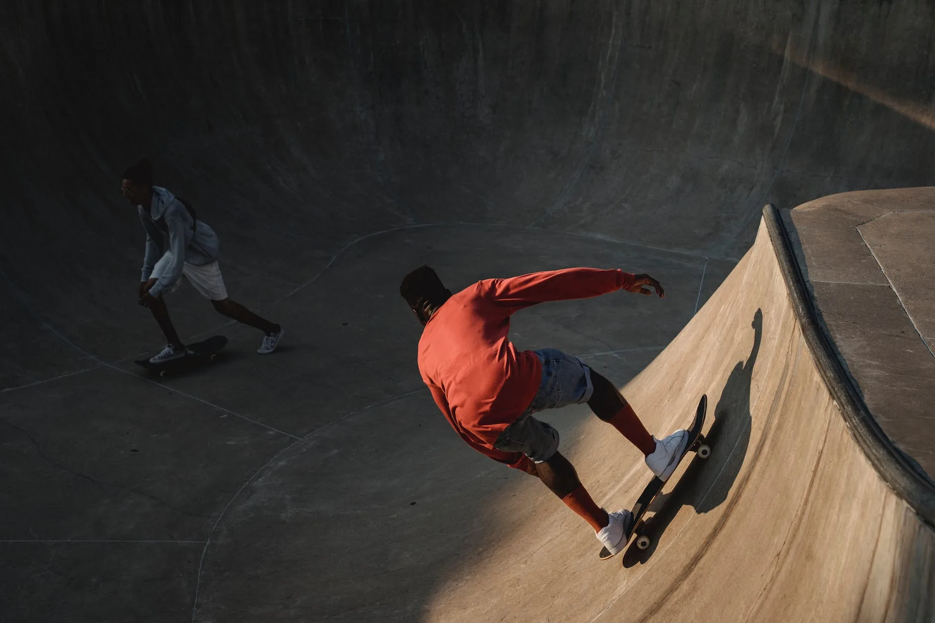 unrecognizable ethnic friends skateboarding on skate ramp in evening